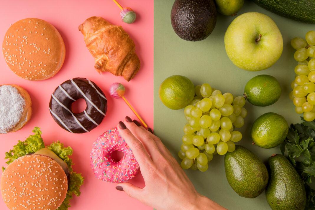 top-view-unhealthy-food-versus-healthy-foodwith-hand-holding-donut